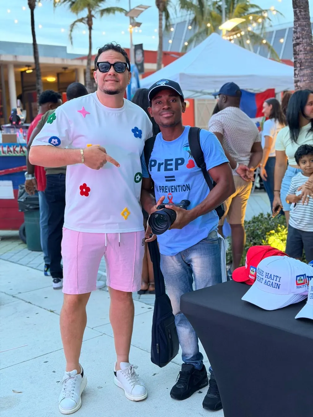 Two people at an outdoor event, one holding a camera